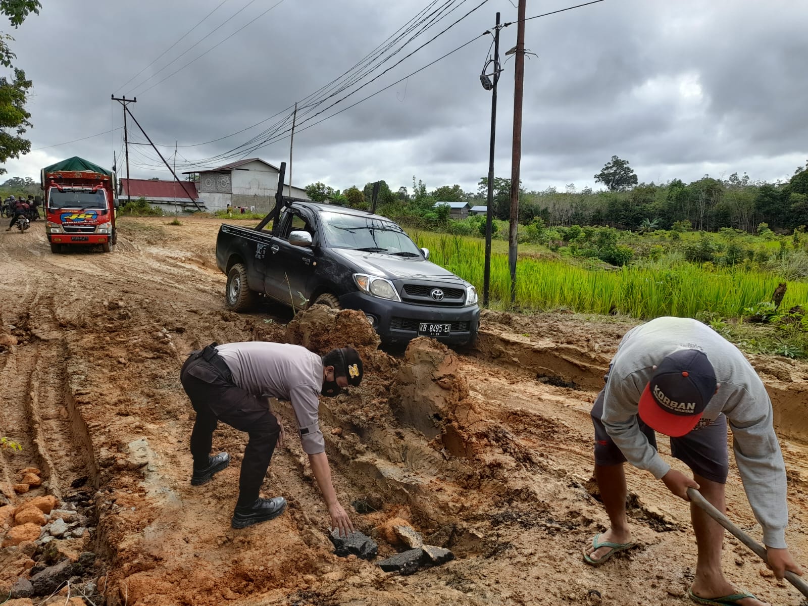 Bentuk Kepedulian, Personel Polsek Pengkadan Laksanakan Pengaturan Lalu Lintas dan Bantu Warga Perbaiki Jalan Rusak