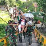 7 orang personel Pos Panga menandu salah seorang warganya sejauh 5 kilometer, untuk melakukan medical check-up pasca operasi ke Rumah Sakit Umum Sanggau, Rabu (22/06/2022). (Foto: Istimewa)