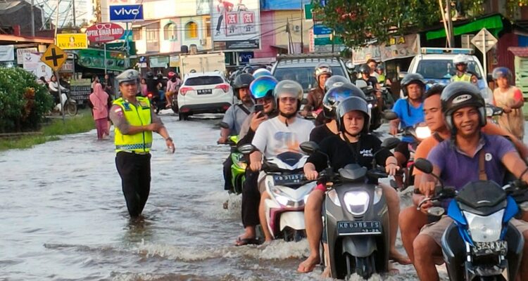 Petugas Satlantas Polres Kapuas Hulu mengatur lalu lintas di ruas jalan yang terdampak banjir di Kota Putussibau. (Foto: Ishaq)